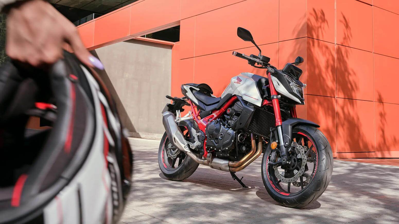 אופנוע נייקד הונדה HORNET 750 E-Clutch בצבע לבן ואדום במבט קדמי אלכסוני בסביבה עירונית